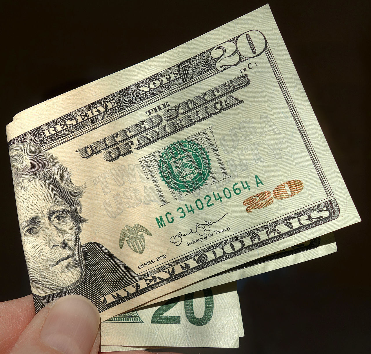 Una mano sostiene billetes de 20 dólares doblados